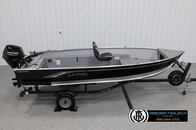 The Image of 2026 Lund 1600 Fury Tiller boat on trailer, featuring Mercury engine, in showroom. - 1