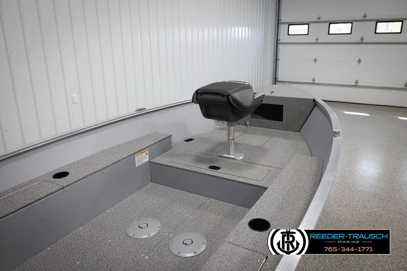 Slide: The Image of 2026 Lund 1600 Fury Tiller boat interior in a showroom, featuring seating and storage. - 15