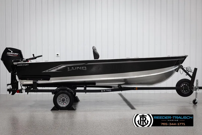 Slide: The Image of Lund 1600 Fury Tiller 2026 boat on trailer, side view, in showroom setting. - 3