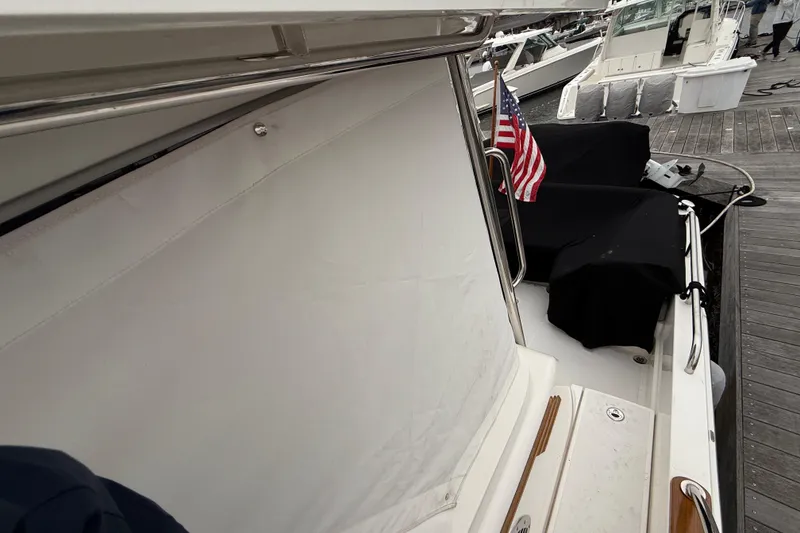 Slide: The Image of 2023 Sabre 43 Salon Express yacht docked, featuring American flag and covered seating area. - 103