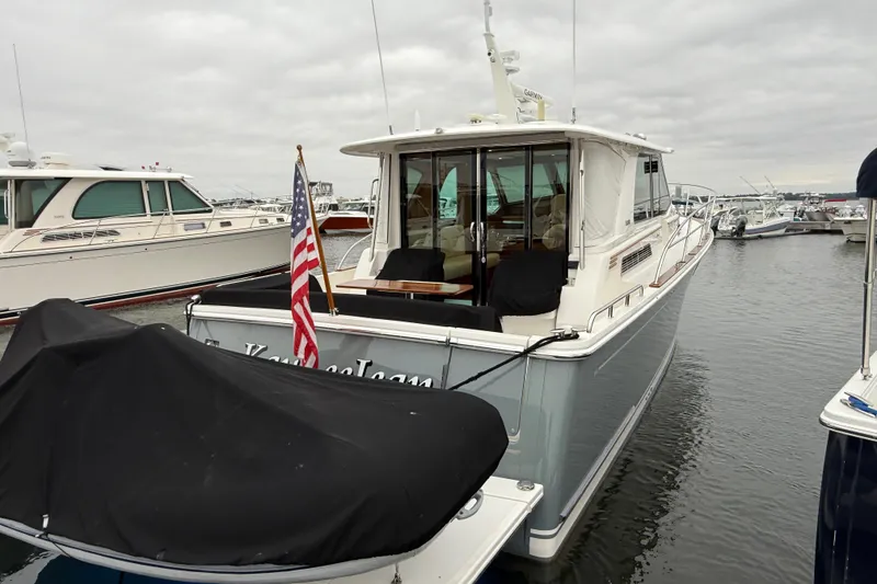 Slide: The Image of 2023 Sabre 43 Salon Express yacht docked in a marina, rear view with American flag. - 110