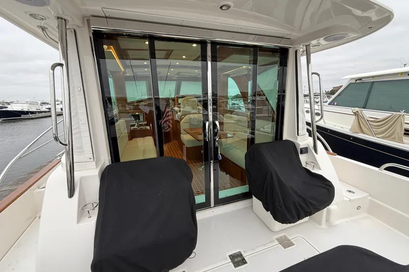 Slide: The Image of 2023 Sabre 43 Salon Express yacht with covered seating and glass doors at a marina. - 113