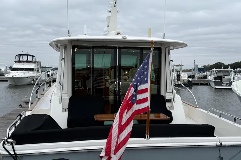Slide: The Image of 2023 Sabre 43 Salon Express yacht docked with American flag, overcast sky. - 3