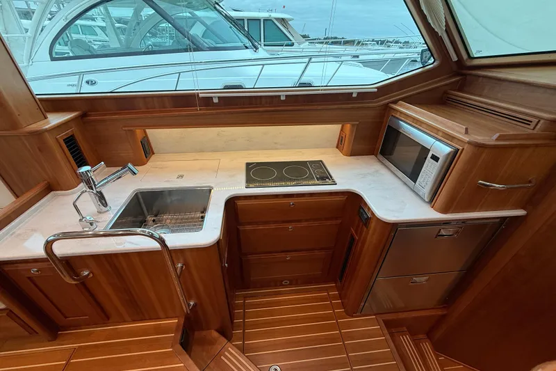 Slide: The Image of 2023 Sabre 43 Salon Express yacht kitchen with wood cabinetry, sink, stove, and microwave. - 40