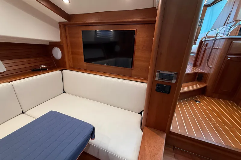 Slide: The Image of 2023 Sabre 43 Salon Express interior with white seating, wood paneling, and a mounted TV. - 60