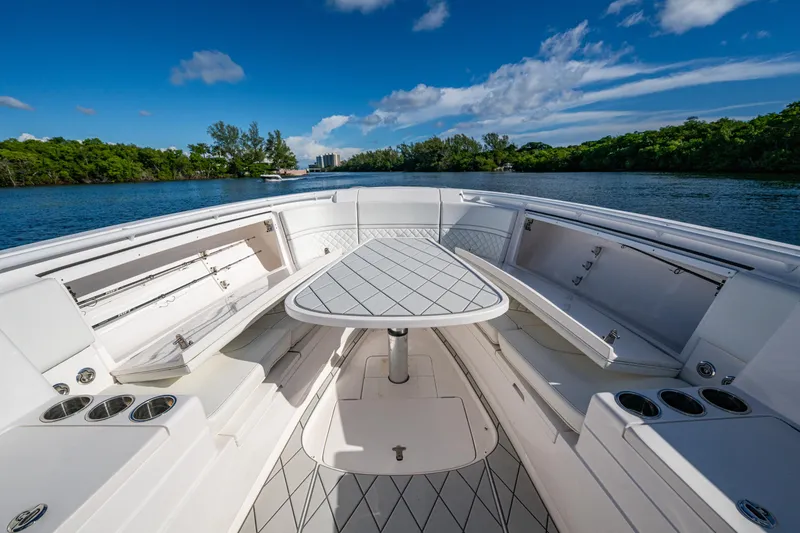 Slide: The Image of 2020 Intrepid 375 Nomad SE boat interior with seating and table on a sunny day. - 15