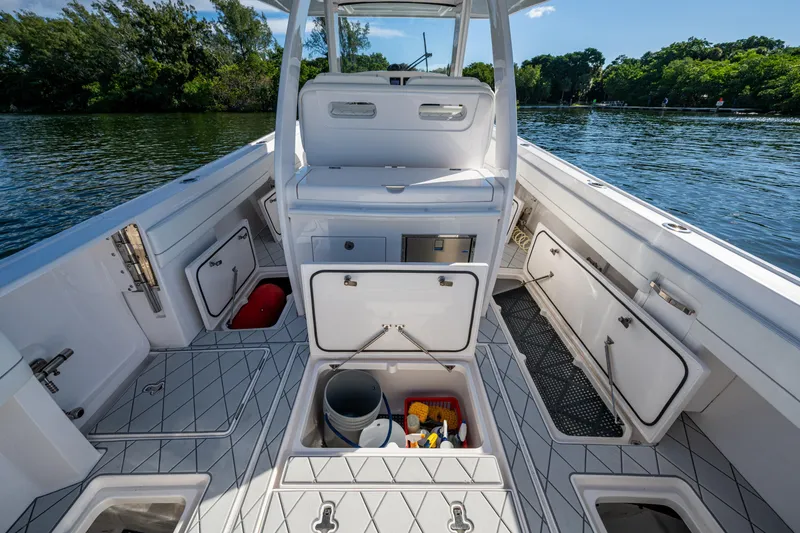 Slide: The Image of 2020 Intrepid 375 Nomad SE boat interior with open storage compartments on a calm lake. - 28