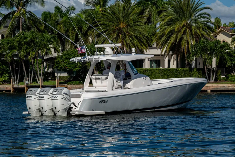 Slide: The Image of 2020 Intrepid 375 Nomad SE boat cruising on water with palm trees in background. - 7