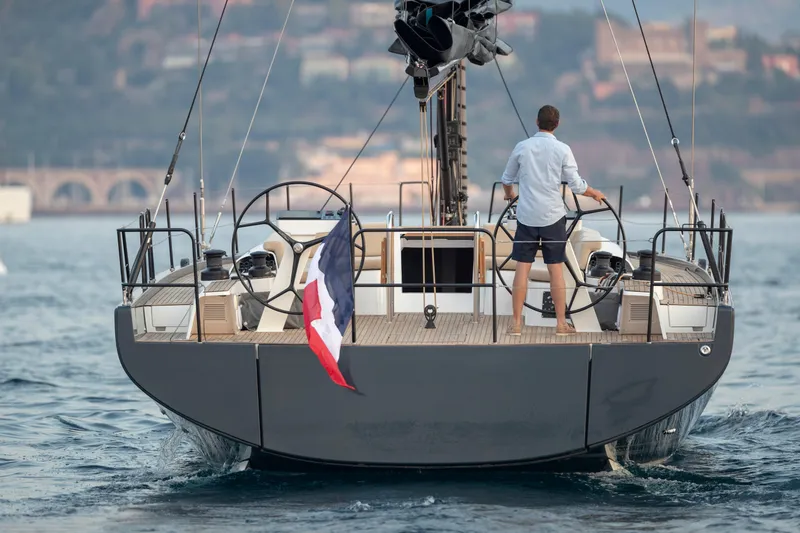 Slide: The Image of 2026 Beneteau First 53 yacht sailing with a person at the helm, rear view. - 41