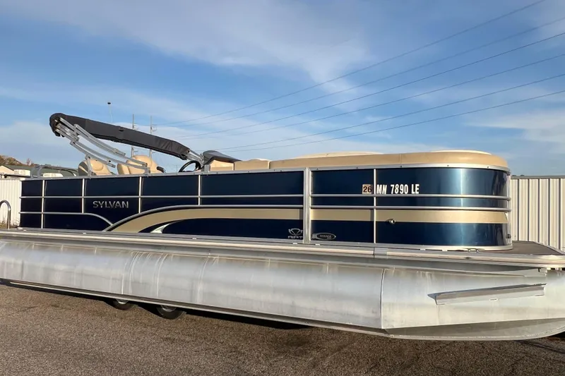 The Image of 2015 Sylvan Mirage Fish 8522 Party Fish LE pontoon boat, blue and beige, parked outdoors. - 0