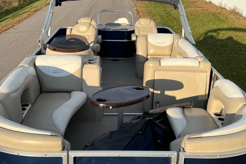 Slide: The Image of 2015 Sylvan Mirage Fish 8522 Party Fish LE pontoon boat interior with beige seating and table. - 2
