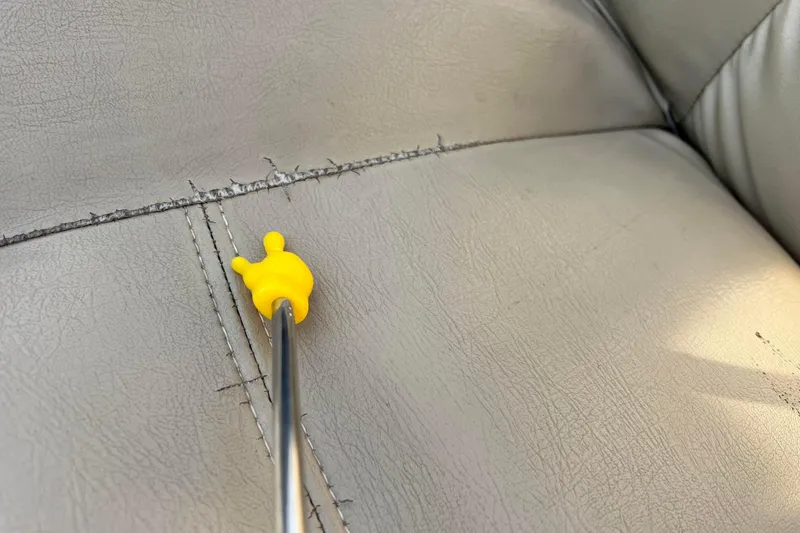 Slide: The Image of A yellow tool on a stitched gray leather seat of a 2015 Sylvan Mirage Fish 8522. - 50