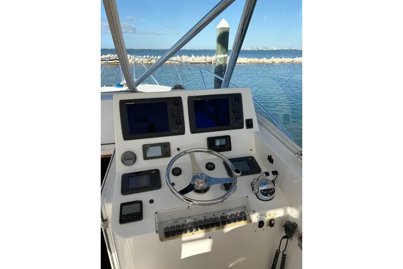 Slide: The Image of 2006 Topaz Express Cruiser helm with navigation screens and steering wheel, overlooking calm waters. - 13