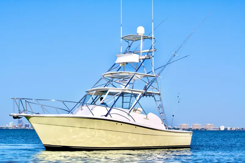 Slide: The Image of 2006 Topaz Express Cruiser yacht on calm blue water with city skyline background. - 2