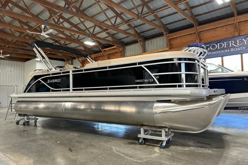 Slide: The Image of 2026 Godfrey SWEETWATER 2286 SB pontoon boat in a wooden-roofed showroom. - 3
