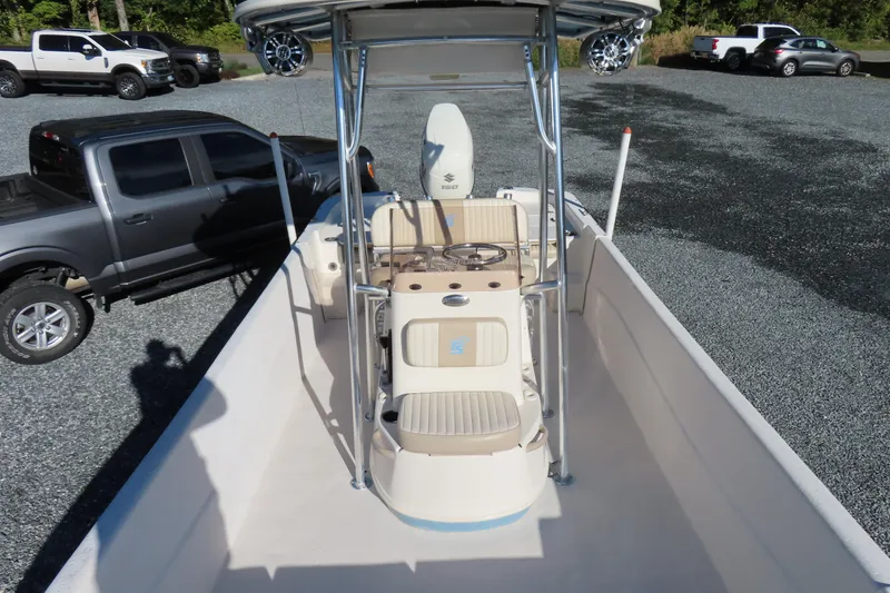 Slide: The Image of 2017 Carolina Skiff 238 DLV boat interior with steering console, parked trucks in background. - 13