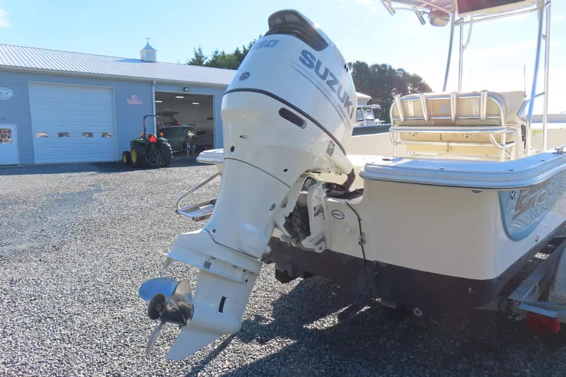 Slide: The Image of 2017 Carolina Skiff 238 DLV with Suzuki outboard motor, parked on gravel near a garage. - 4