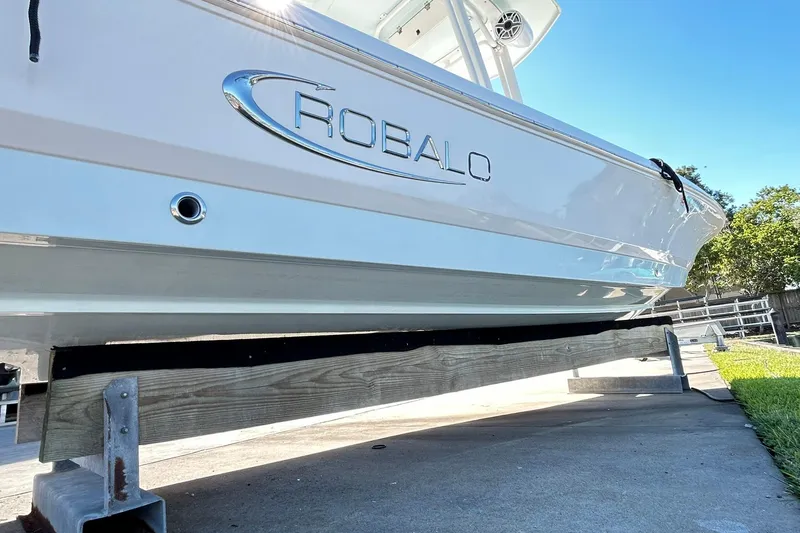 Slide: The Image of 2019 Robalo 226 Cayman boat on a lift, showcasing sleek design and branding. - 12