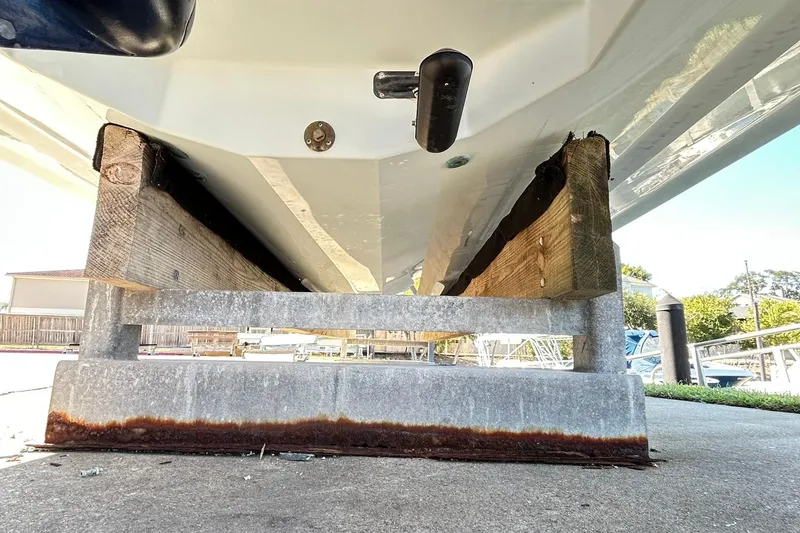Slide: The Image of 2019 Robalo 226 Cayman boat hull on wooden supports, dockside view. - 21