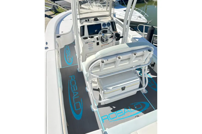 Slide: The Image of 2019 Robalo 226 Cayman boat interior with helm, seating, and branded flooring. - 24