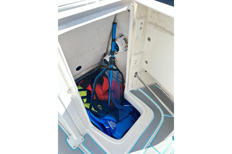 Slide: The Image of Storage compartment of 2019 Robalo 226 Cayman boat with life jackets and net. - 35