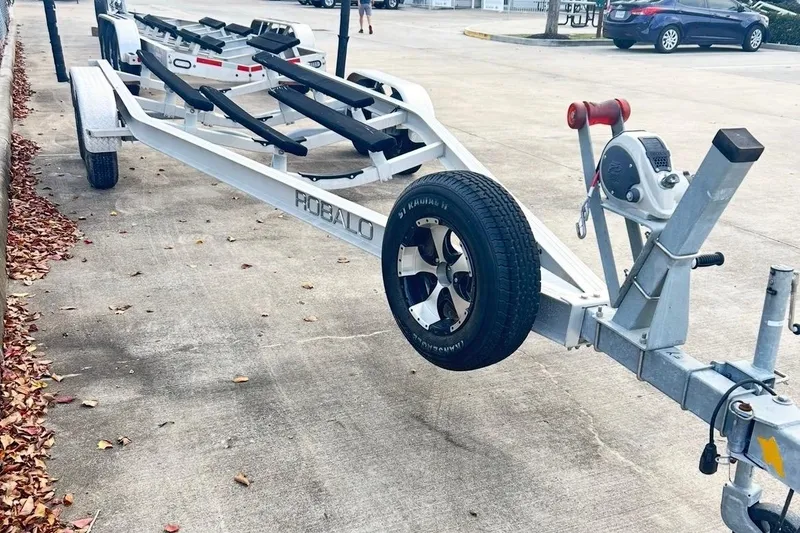 Slide: The Image of 2019 Robalo 226 Cayman boat trailer parked on concrete with autumn leaves. - 64
