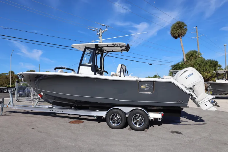 Slide: The Image of 2026 Sea Hunt Ultra 275 SE boat on trailer, parked outdoors under clear blue sky. - 13