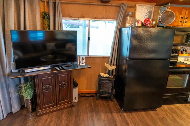 Slide: The Image of Interior of 1989 Seabreeze houseboat with TV, refrigerator, and kitchen area. - 13