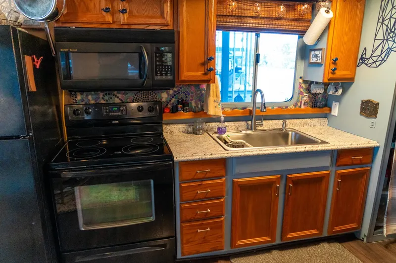 Slide: The Image of 1989 Seabreeze houseboat kitchen with wooden cabinets, granite countertops, and modern appliances. - 15