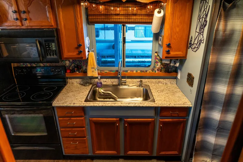 Slide: The Image of 1989 Seabreeze houseboat kitchen with wooden cabinets, granite countertop, and stainless steel sink. - 16