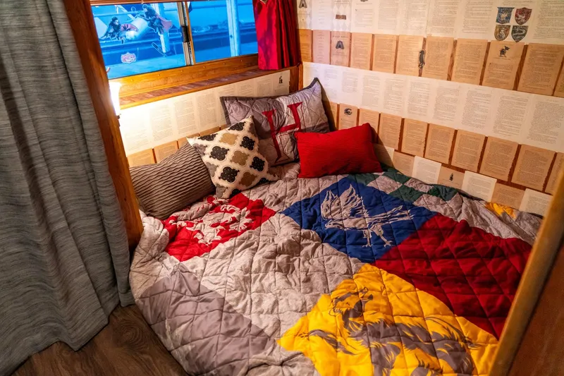Slide: The Image of Cozy houseboat bedroom with colorful quilt, decorative pillows, and book-themed wallpaper. - 22