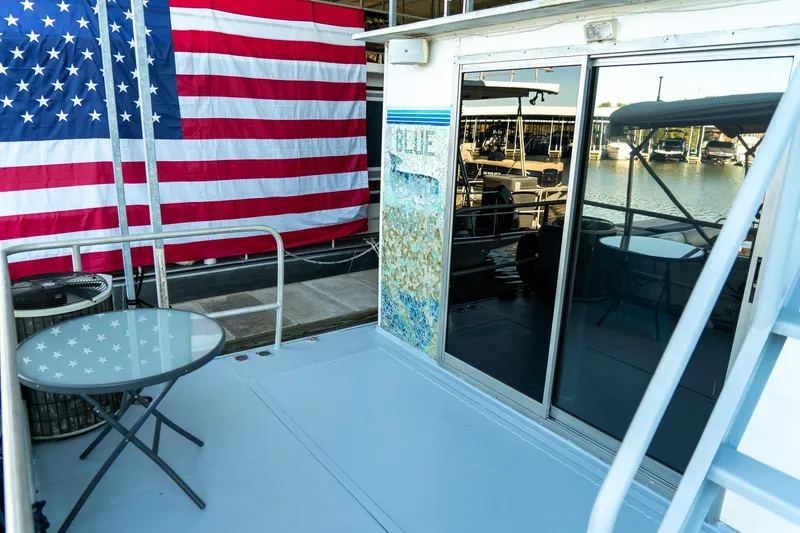 Slide: The Image of 1989 Seabreeze houseboat deck with American flag and glass table, marina view. - 26
