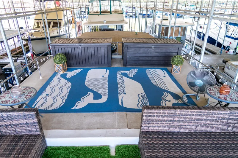 Slide: The Image of 1989 Seabreeze houseboat deck with whale-themed rug, wicker seating, and decorative plants. - 34