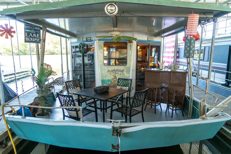 Slide: The Image of 1989 Seabreeze 53 x 14 houseboat with outdoor seating and decor, docked at a marina. - 5