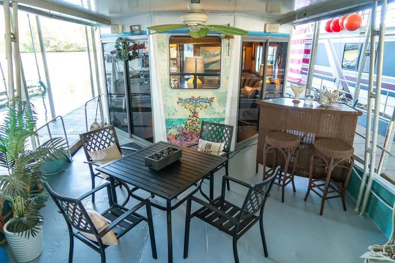 Slide: The Image of 1989 Seabreeze houseboat interior with patio furniture, bar stools, and decorative plants. - 6