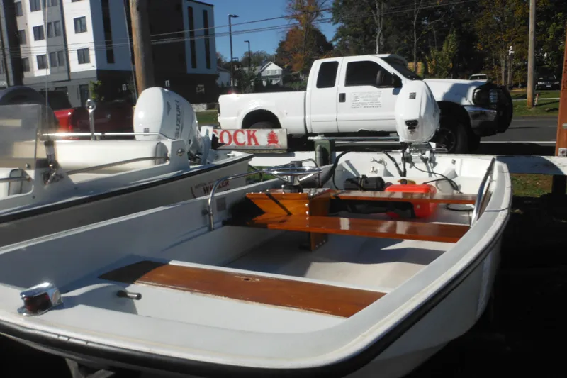 Slide: The Image of 1973 Boston Whaler 13 Sport Side boat with wooden seats, parked near a white truck. - 3