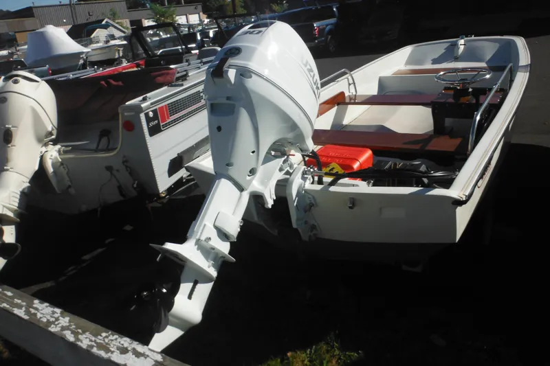 Slide: The Image of 1973 Boston Whaler 13 Sport Side boat with outboard motor, parked outdoors. - 6