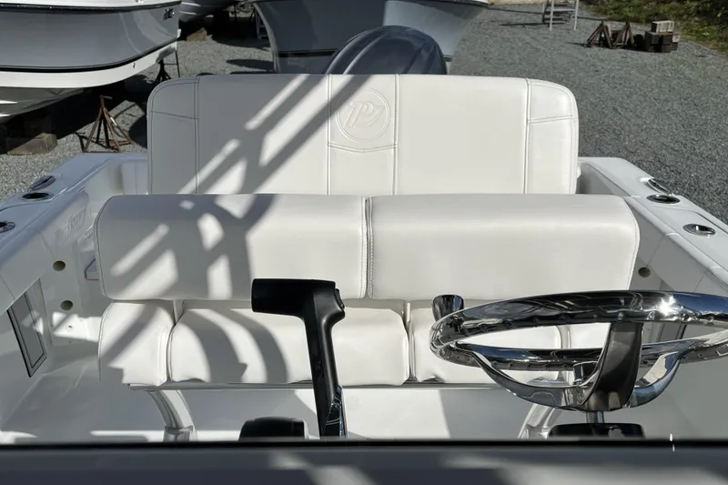 Slide: The Image of 2026 Parker 210 Coastal boat interior with white seating and chrome steering wheel. - 5