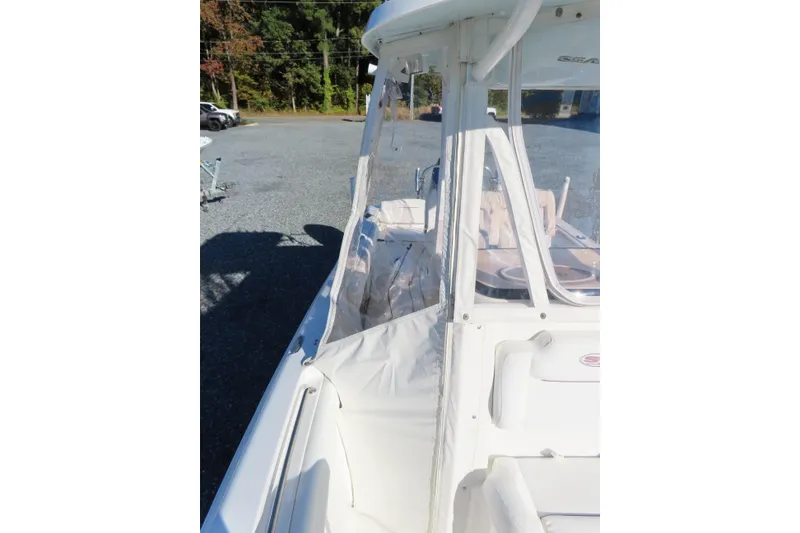 Slide: The Image of 2018 Sea Hunt Ultra 234 boat with protective enclosure, parked on gravel. - 13