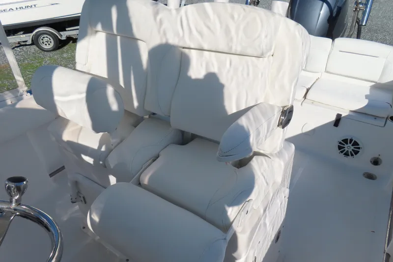 Slide: The Image of 2018 Sea Hunt Ultra 234 boat with white cushioned seating and steering wheel. - 18