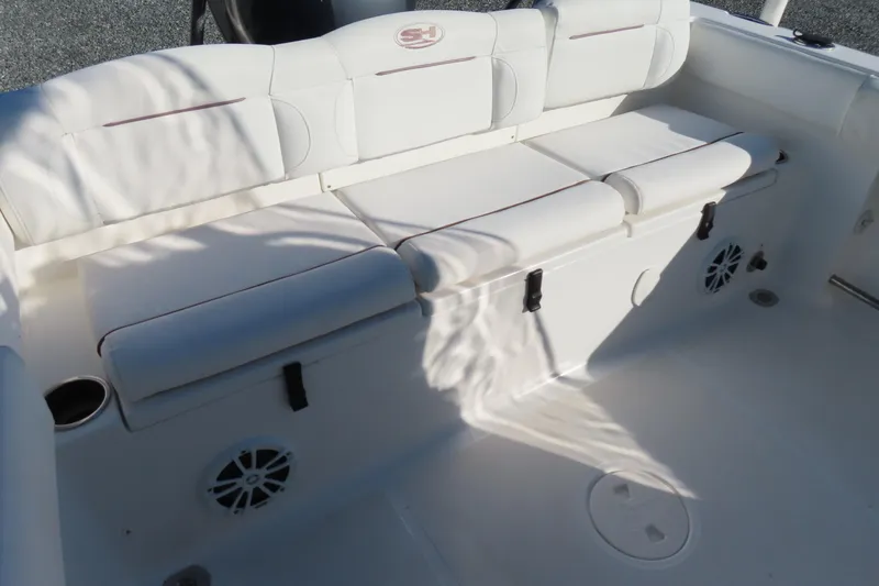 Slide: The Image of 2018 Sea Hunt Ultra 234 boat interior with white cushioned seating and built-in speakers. - 28