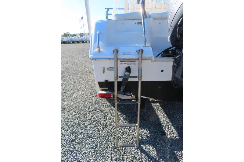 Slide: The Image of 2018 Sea Hunt Ultra 234 boat with rear ladder on gravel surface. - 6