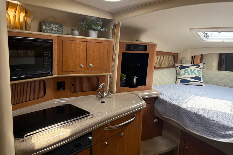 Slide: The Image of 2006 Sea Ray 300 Sundancer interior with kitchenette and cozy sleeping area. - 17