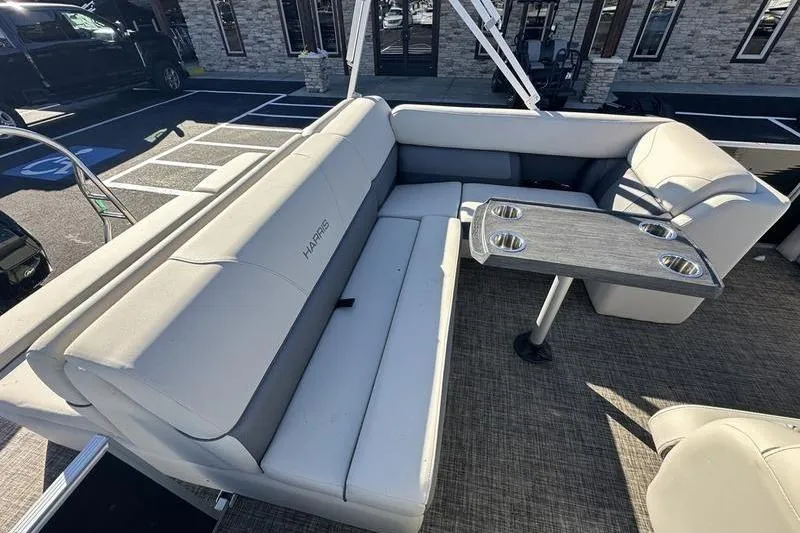 Slide: The Image of 2023 Harris Cruiser 210 CS boat interior with cushioned seating and table, parked outdoors. - 15