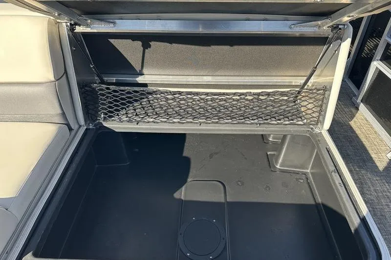 Slide: The Image of 2023 Harris Cruiser 210 CS storage compartment with netting and cushioned seating. - 20