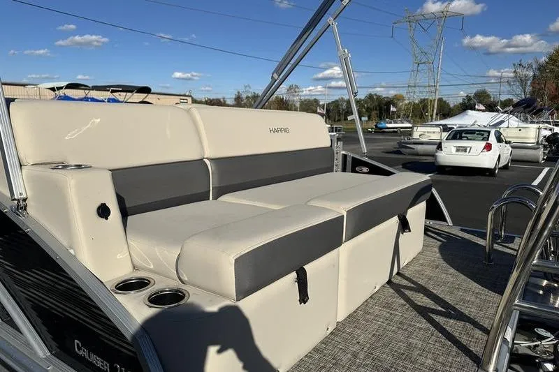 Slide: The Image of 2023 Harris Cruiser 210 CS boat with beige seating and cup holders, parked outdoors. - 3