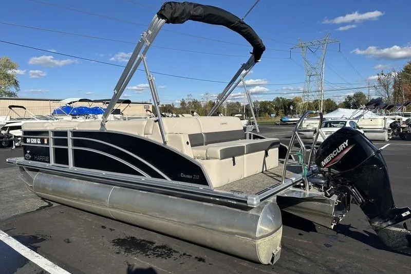 Slide: The Image of 2023 Harris Cruiser 210 CS pontoon boat with Mercury outboard motor, parked outdoors. - 4