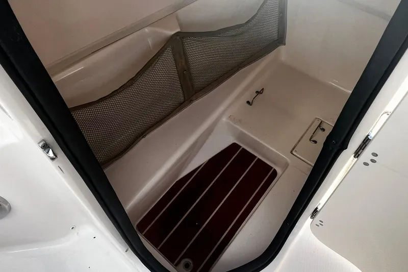 Slide: The Image of 2013 Grady-White Freedom 205 boat interior storage compartment with netting and wooden floor mat. - 33