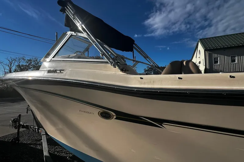 Slide: The Image of 2013 Grady-White Freedom 205 boat with canopy, parked outdoors under blue sky. - 6