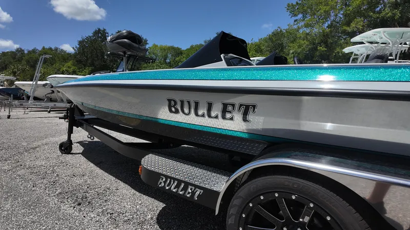 Slide: The Image of 2025 Bullet 21SDC boat on trailer, metallic finish, parked outdoors under blue sky. - 11